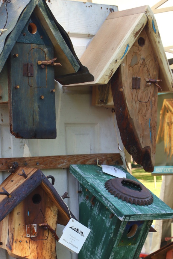 Colorful handmade birdhouses displayed outdoors at a market