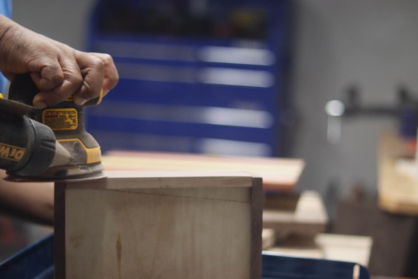 Carl sanding the edge of a wooden box with an orbital sander