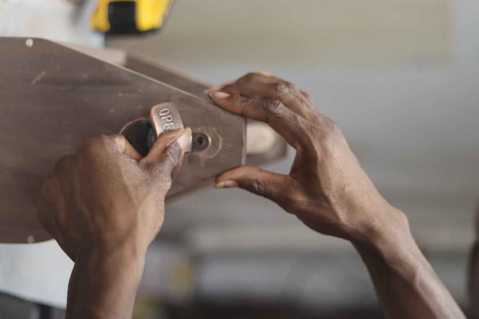 Carl fitting a small brass OPEN tag onto a dark wooden piece