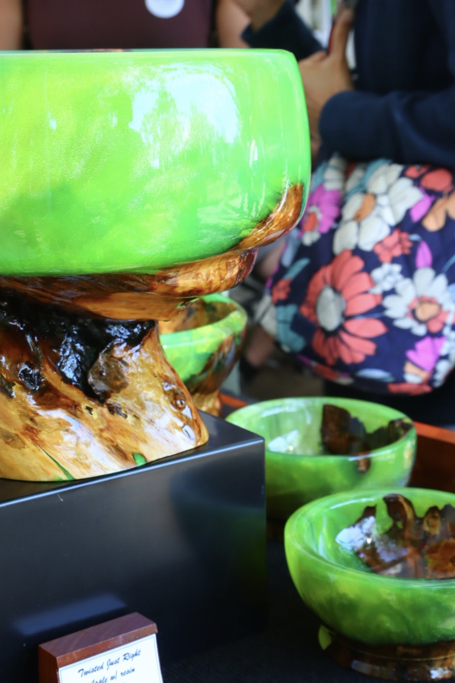 Glossy green resin and wood bowls and sculptural pieces displayed at an exhibition